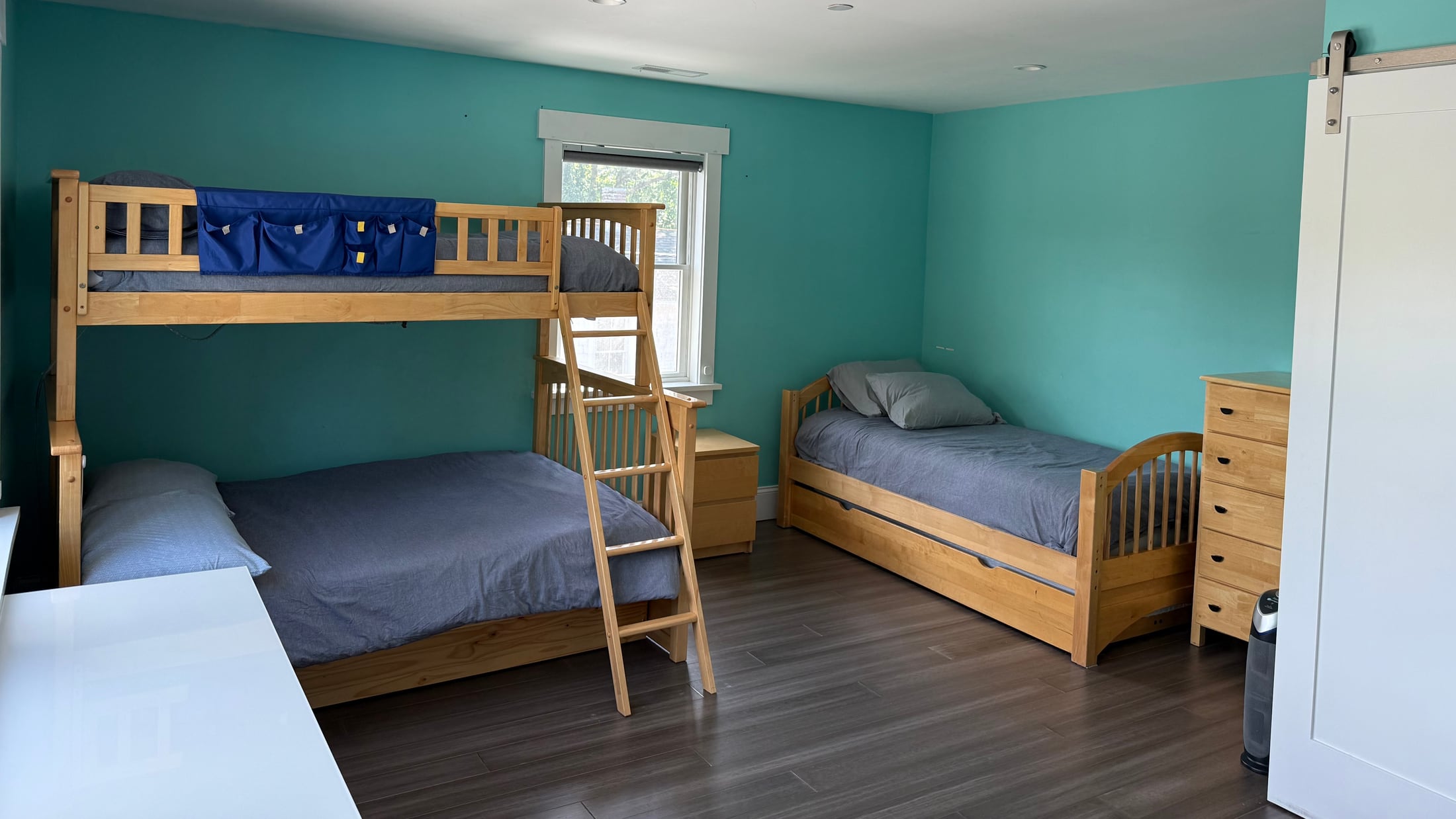 Spacious blue bedroom with a wooden bunk bed and two additional beds