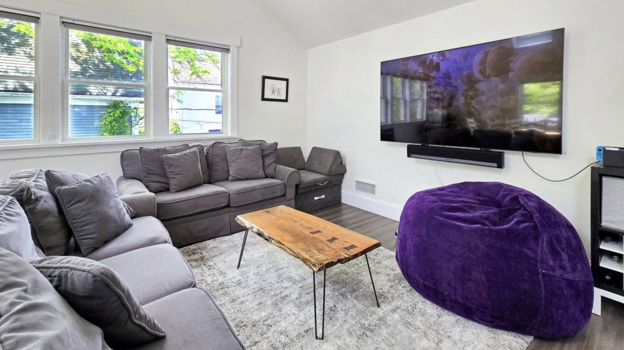 Media lounge with sectional sofa, large television, and purple beanbag
